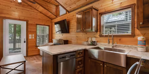Interior of a luxury cottage kitchen at Splash RV Resort featuring wood walls and stainless steel appliances.