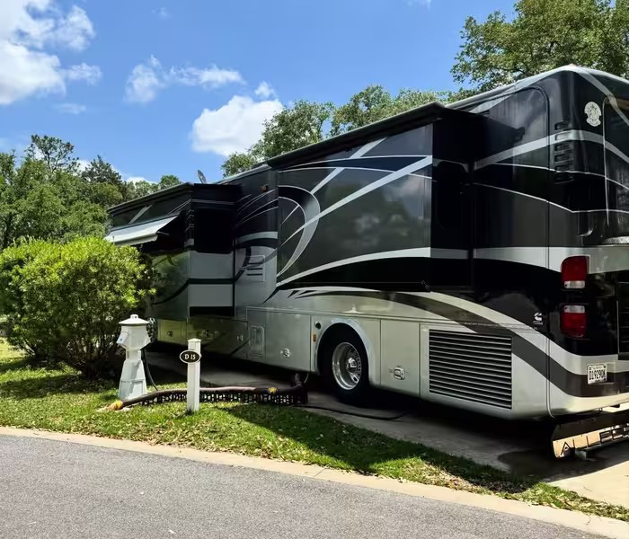 Luxury motorhome parked at Splash RV Resort with slide-outs extended under a blue sky.