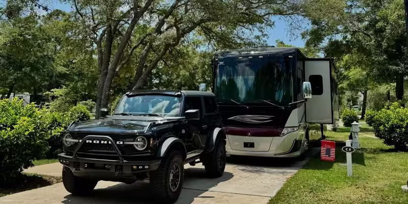 Luxury motorhome and Ford Bronco parked at a scenic campsite at Splash RV Resort.