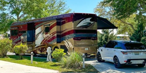 Luxury motorhome parked at Splash RV Resort with a white SUV and manicured landscaping.