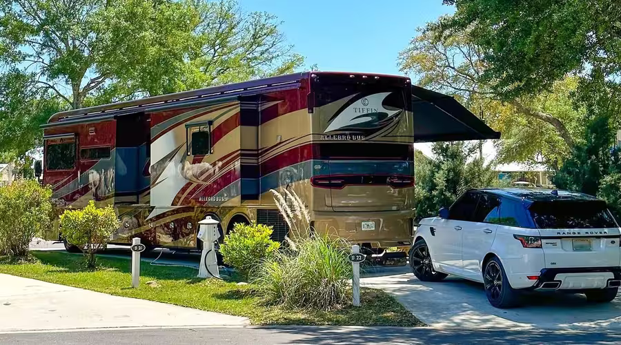 Luxury motorhome parked at Splash RV Resort with a white SUV and manicured landscaping.