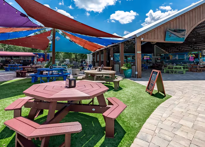 Colorful shade sails cover the outdoor dining pavilion at Splash RV Resort, providing shade for picnic tables and guests.