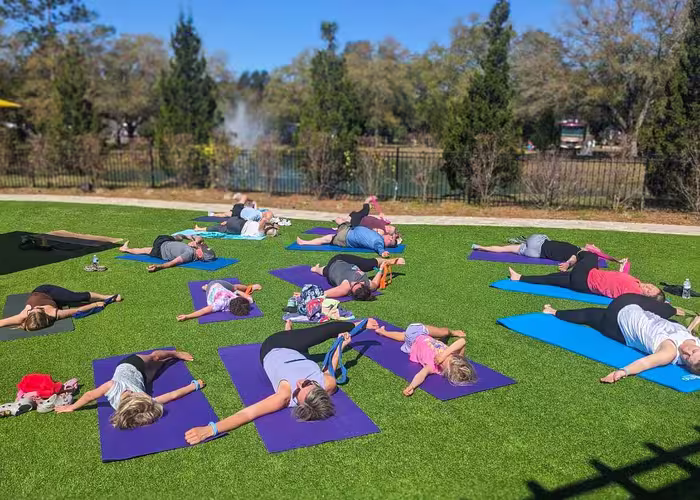 A group doing outdoor yoga on a green lawn with a lake view at Splash RV Resort in Milton, Florida