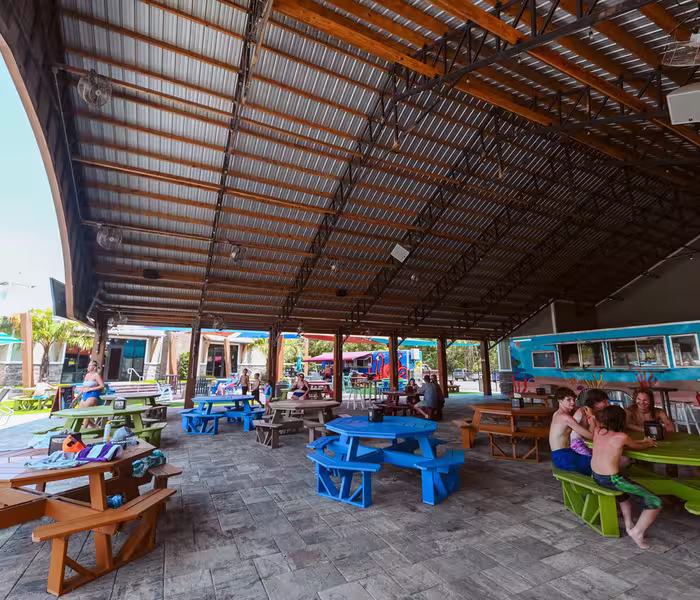 Pavilion with colorful octagonal picnic tables and ocean-themed concession stand at Splash RV Resort in Milton, Florida.