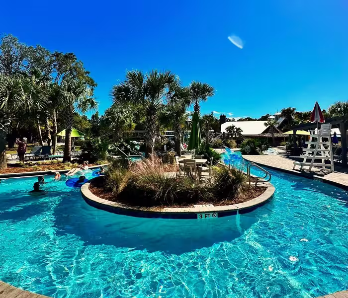Guests enjoying the resort pool at Splash RV Resort, featuring a central island and palm trees.