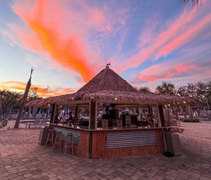 Tiki bar at Splash RV Resort under a vibrant pink and orange sunset sky.