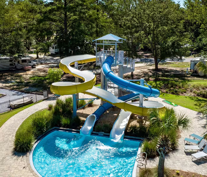 Aerial view of twin twisting water slides splashing into a sparkling swimming pool at Splash RV Resort.