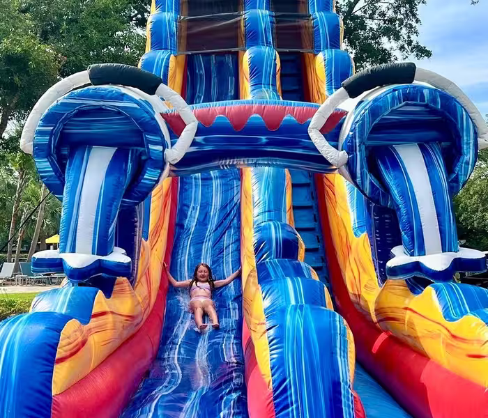 A young girl joyfully sliding down a towering inflatable water slide at Splash RV Resort in Milton, Florida