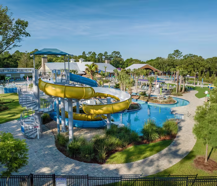 Aerial view of a yellow and blue water slide at Splash RV Resort next to a swimming pool.