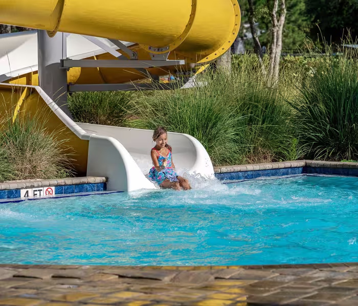 Child splashing into the pool at the bottom of a water slide at Splash RV Resort