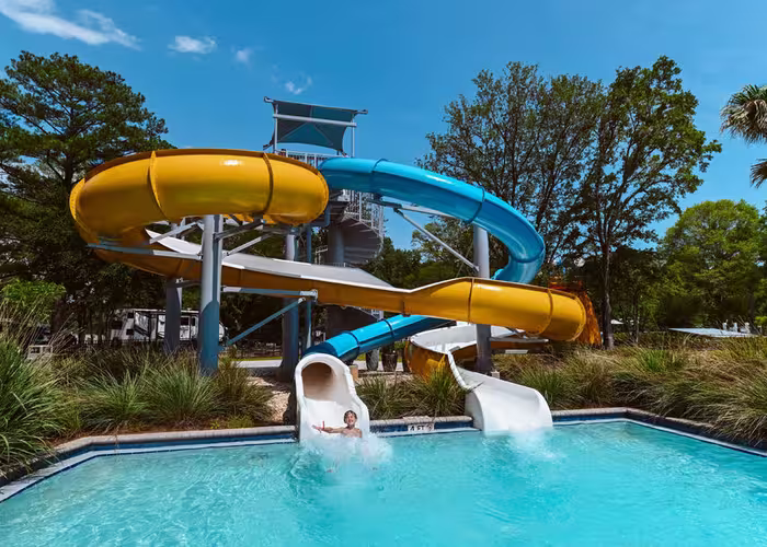 Guest splashing into the pool at the end of twisting yellow and blue water slides at Splash RV Resort.