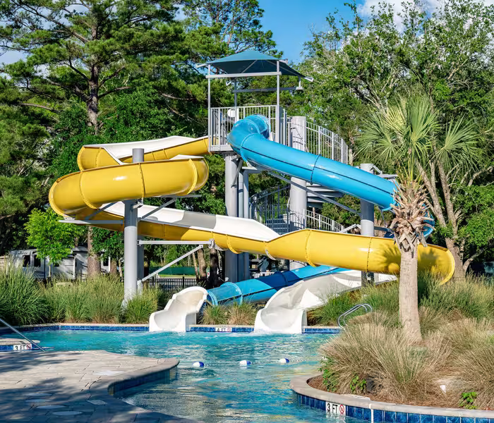 Colorful water slides at Splash RV Resort in Milton, Florida, winding down into a swimming pool surrounded by lush trees.