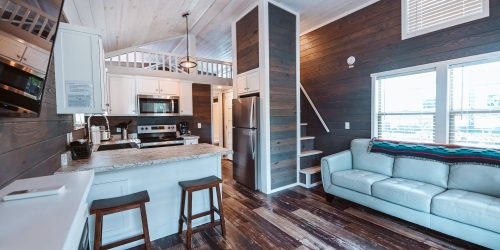 White kitchen island with light blue leather sofa and dark shiplap walls at Splash RV Resort in Milton, Florida.