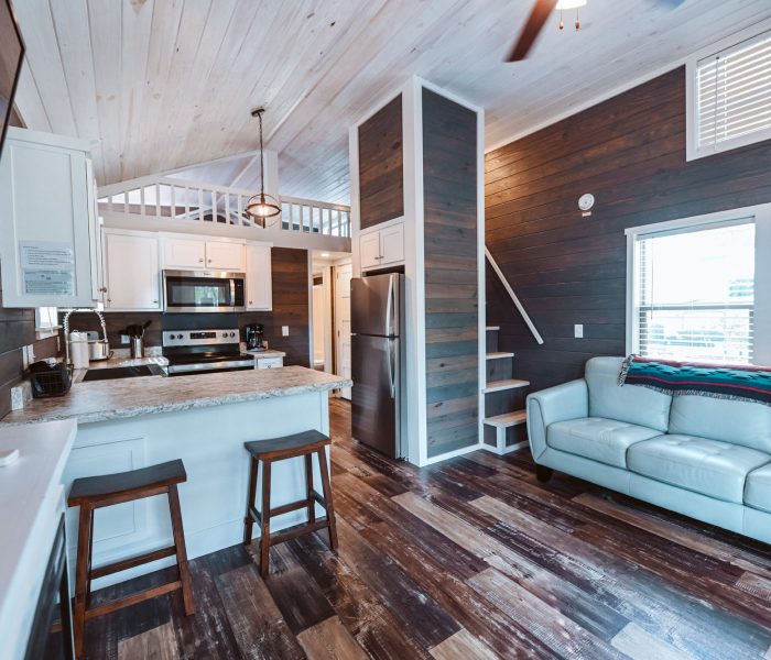 White kitchen island with light blue leather sofa and dark shiplap walls at Splash RV Resort in Milton, Florida.