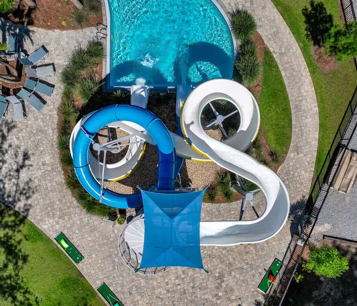 Aerial view of blue and white water slides at Splash RV Resort leading into a sparkling turquoise swimming pool.